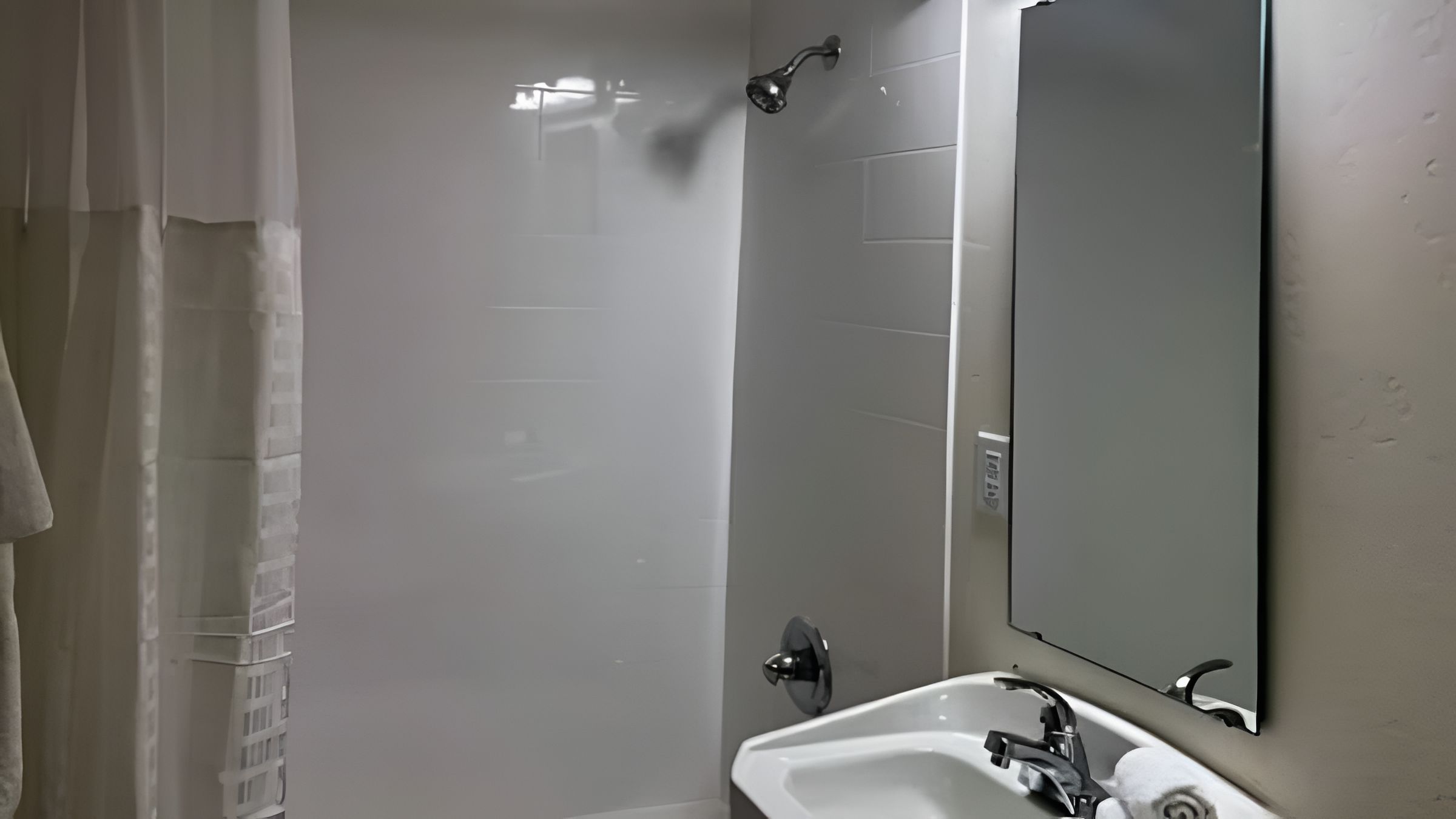 A bathroom with a shower, a sink, and a mirror.