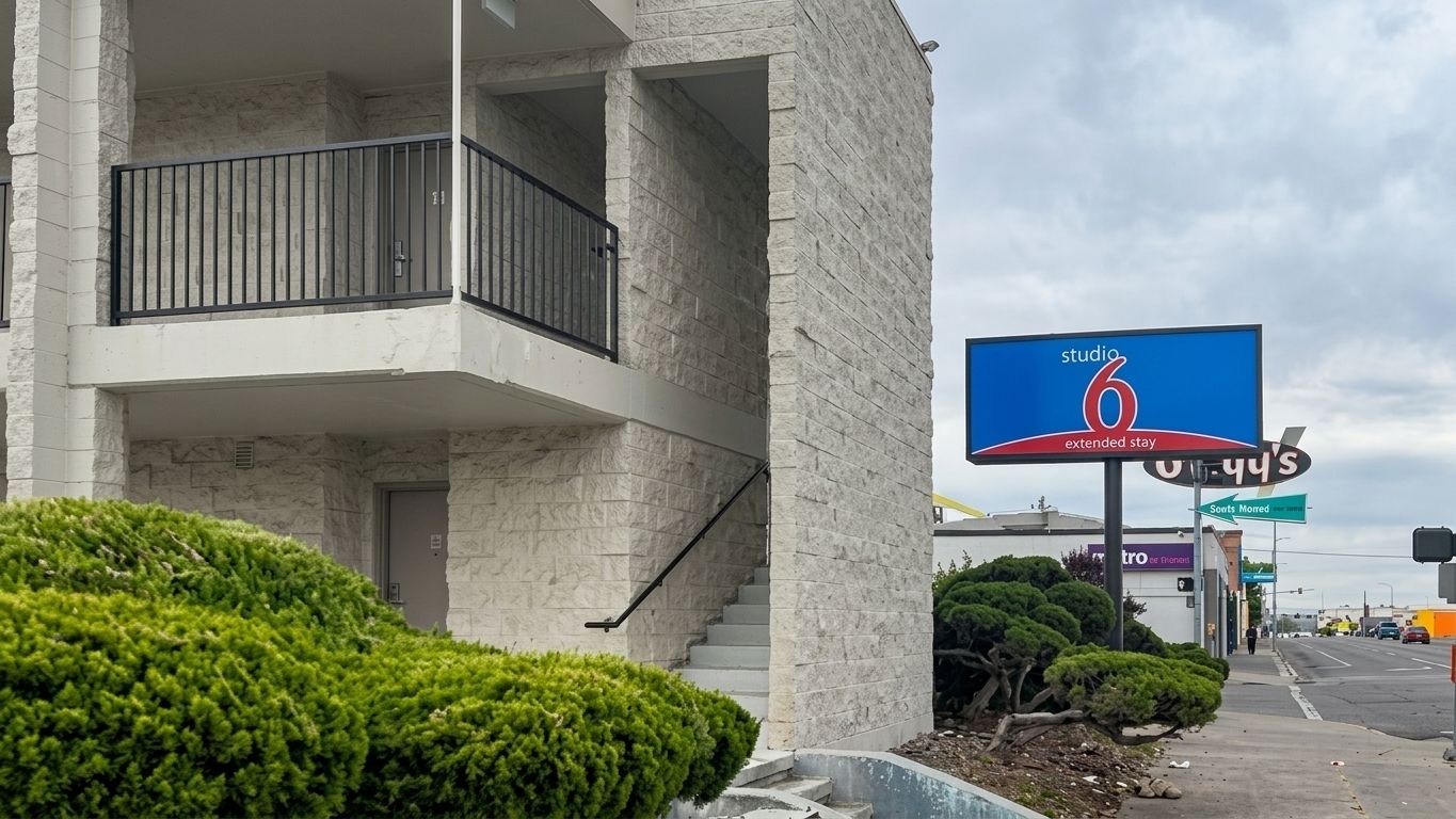 A hotel exterior with a balcony, a sign for 'studio 6 extended stay', and a street view with a traffic light.