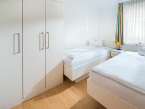 Een hotelkamer met een bed, nachtkastje, lamp en kledingkast.
