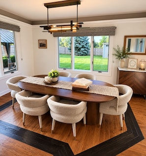 A dining area with a wooden table, six chairs, and a modern pendant light.