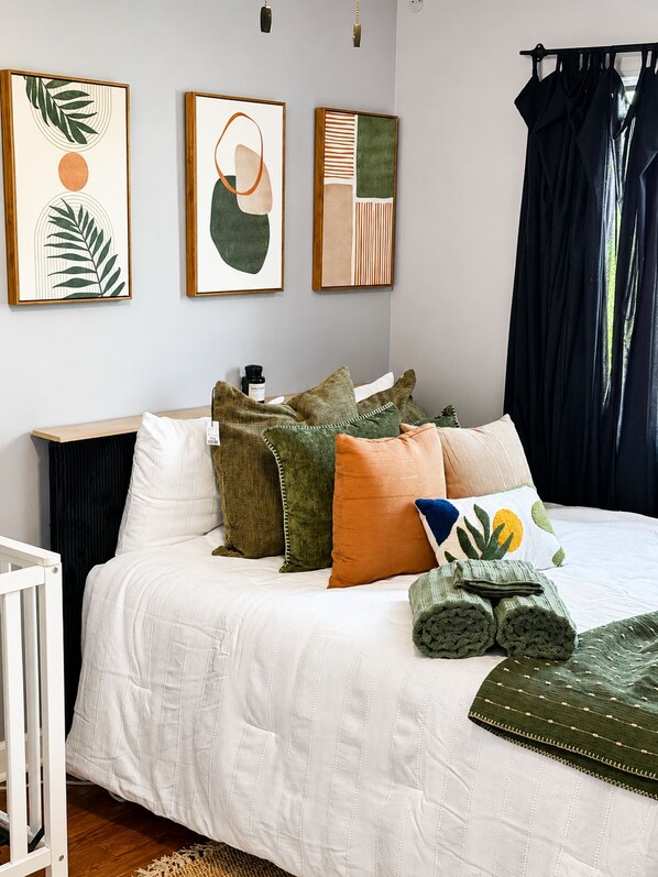 A bedroom with a bed, pillows, a bedside table, and wall art.