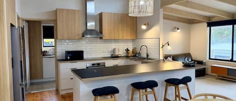 A modern kitchen with a central island, bar stools, and a dining table.