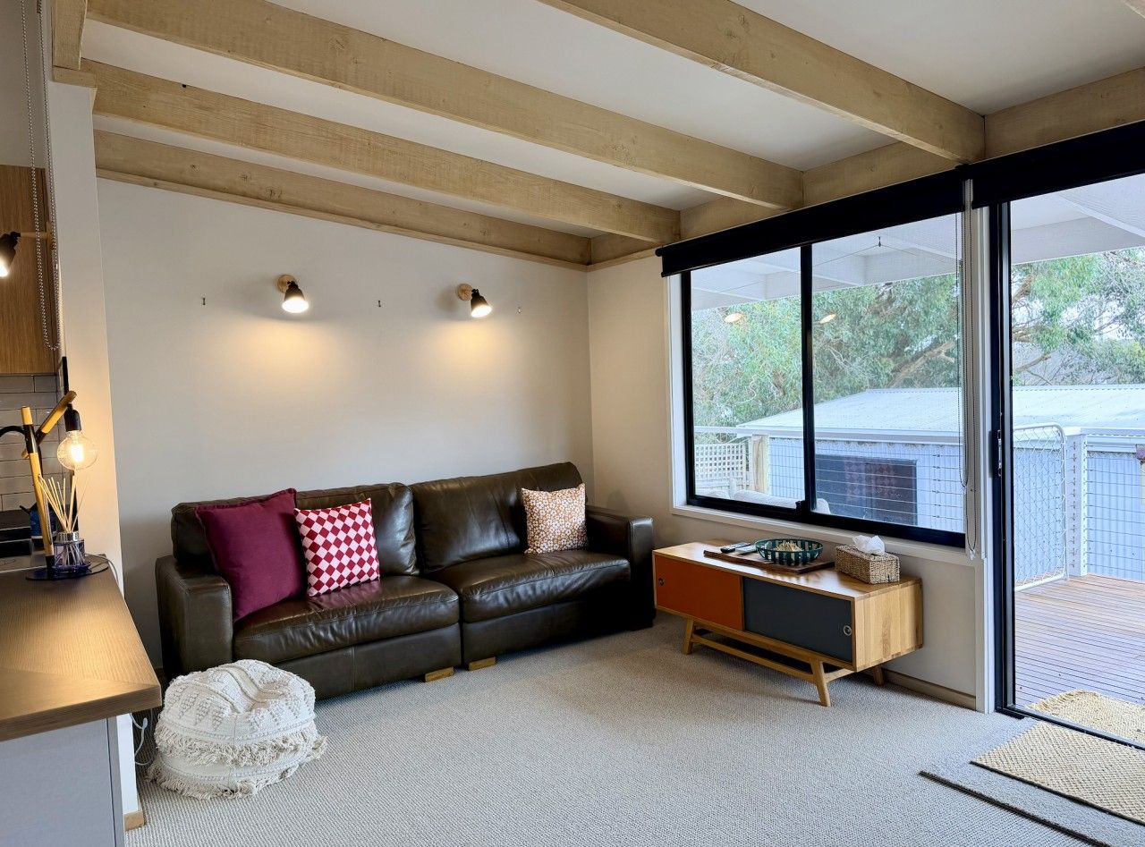 Una sala de estar moderna con un sofá de cuero, una mesa de centro de madera y un amplio ventanal con vistas al exterior.