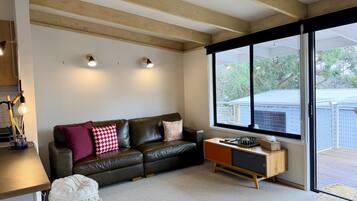Una sala de estar moderna con un sofá de cuero, una mesa de centro de madera y un amplio ventanal con vistas al exterior.