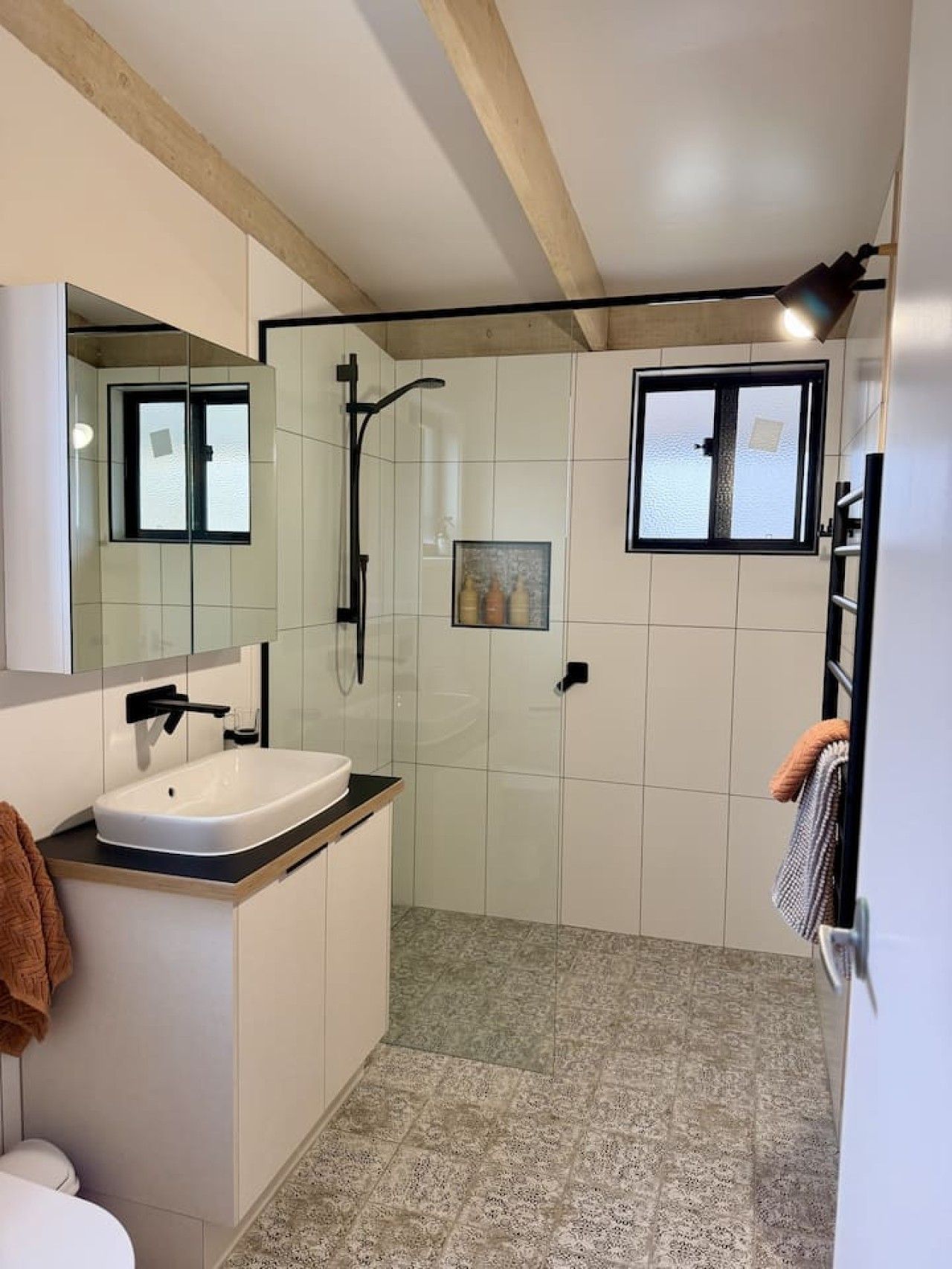 A modern bathroom with a white sink, a glass shower enclosure, and a large mirror.