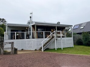 A modern house with a covered porch, a staircase, and a fenced yard. - The Other PC Cottage (Port Campbell)