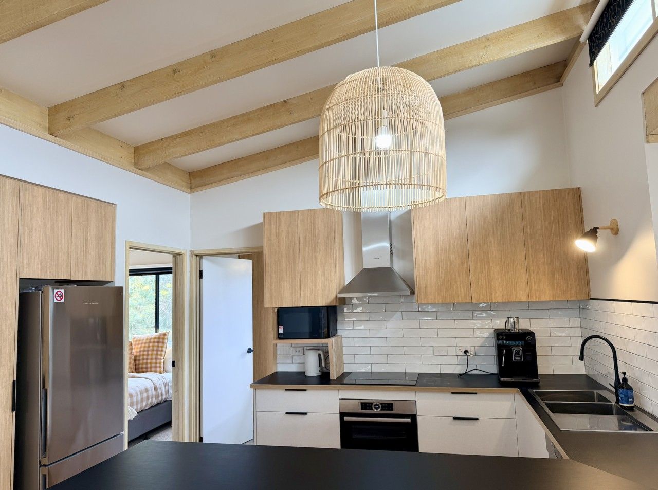 A modern kitchen with wooden cabinets, a stainless steel refrigerator, a microwave, and a built-in oven.