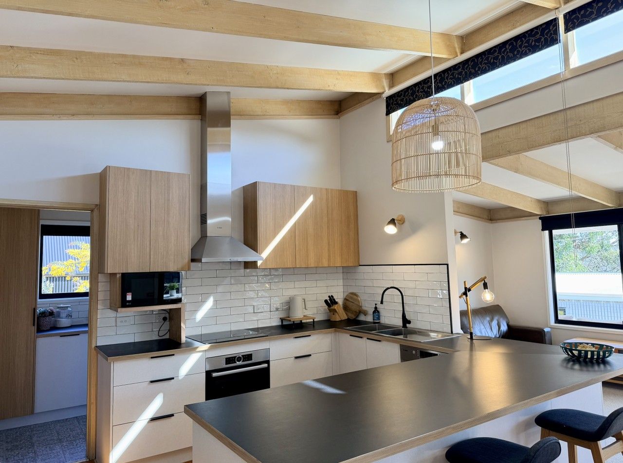 A modern kitchen with wooden cabinets, a central island, and pendant lighting.