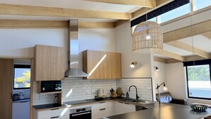 Una cuina moderna amb armaris de fusta, una illa central i il·luminació penjant.