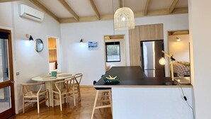 Eine moderne Küche mit Holzbalken, einer zentralen Kochinsel und einer hängenden Leuchte.