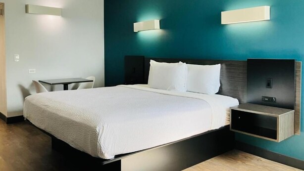 Una habitación de hotel moderna con una cama grande, mesitas de noche y un escritorio.