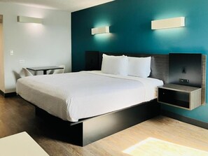 A modern hotel room with a large bed, bedside tables, and a desk.
