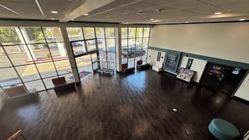 A spacious indoor area with a dark wooden floor, large windows, and a vending machine.