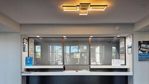 Zona de recepción con mostrador, puertas de vidrio y carteles informativos en las paredes.