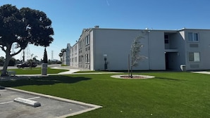 Un edificio moderno con techo plano, un pequeño árbol en el centro y un cielo azul despejado.