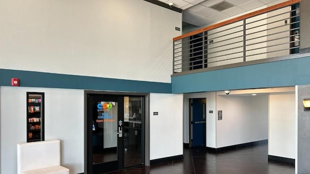 Un'ampia hall con reception, area salotto e una scala che conduce a un piano superiore.
