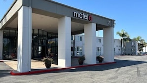 Un motel con ingresso coperto, ampie colonne e cielo sereno.