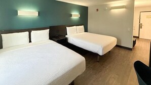 Una camera d'albergo con due letti, un comodino e una sedia.