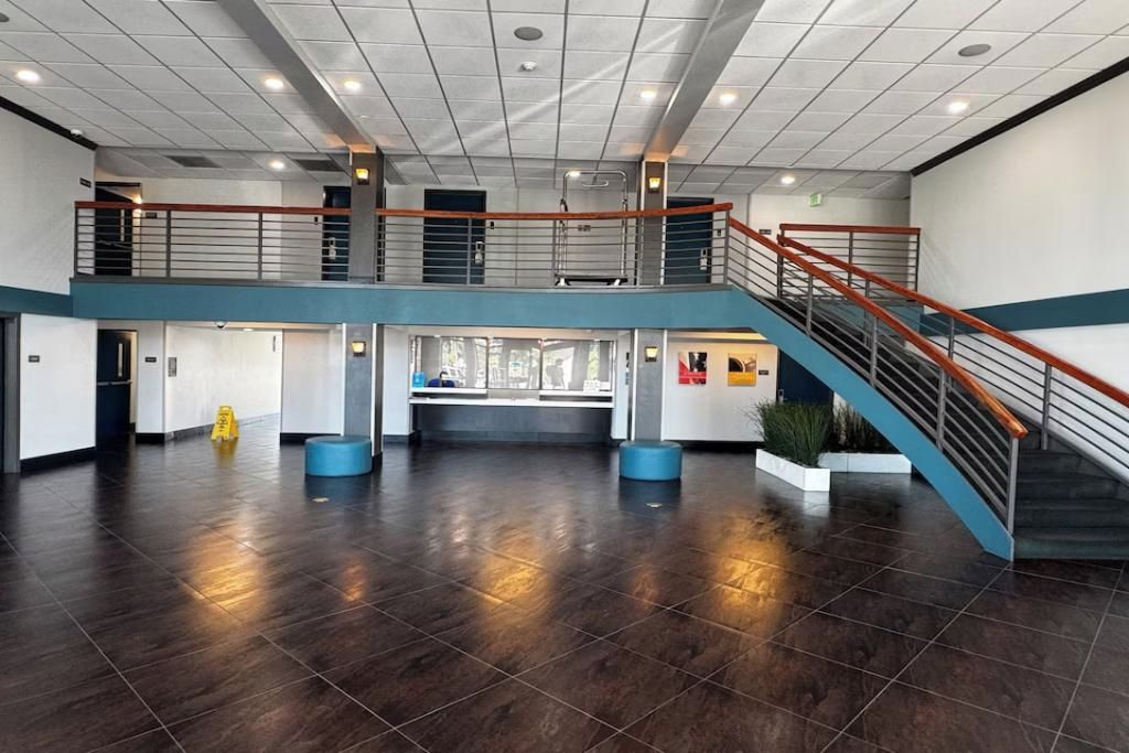 A spacious lobby with a central reception desk, a staircase, and a mezzanine level.
