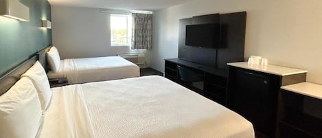 A hotel room with two beds, a flat-screen TV, a desk, and a window with curtains.