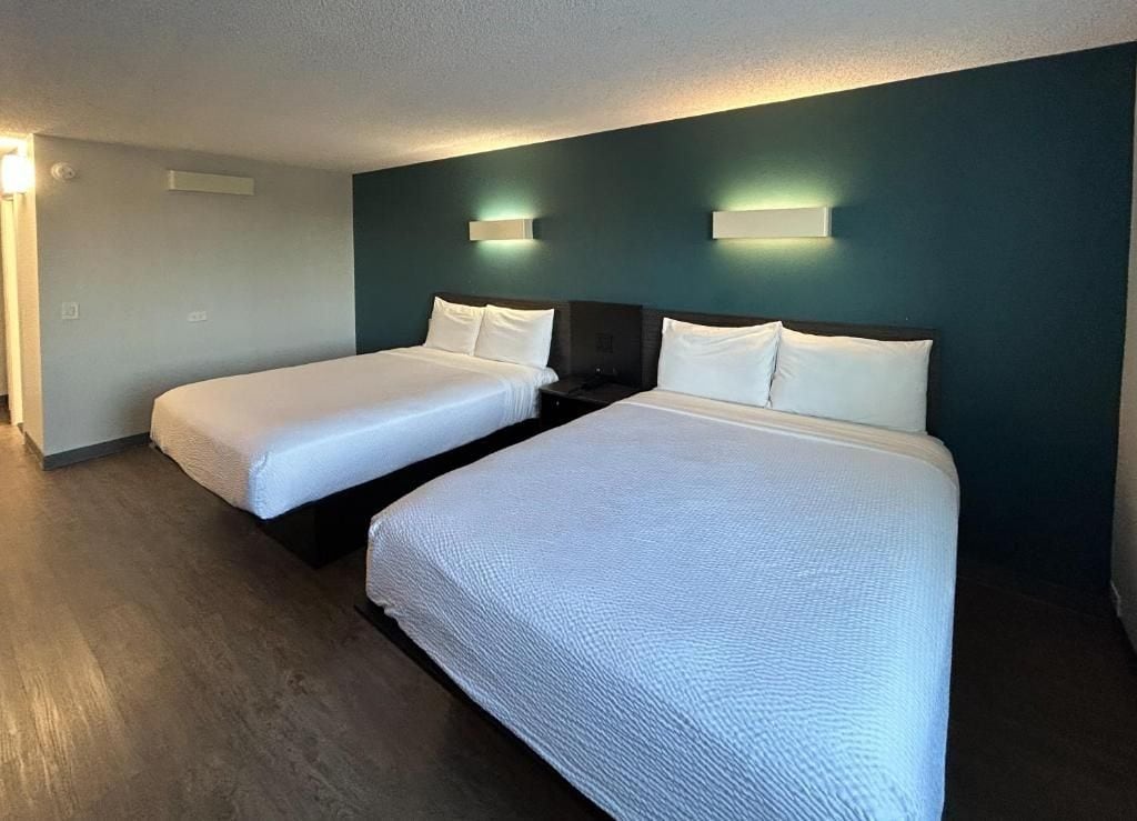 A hotel room with two beds, a dark-colored wall, and a light-colored floor.