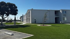 Ein modernes Gebäude mit Flachdach, einer kleinen Pflanze in der Mitte und blauem Himmel.