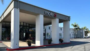 A motel with a covered entrance, large pillars, and a clear sky.