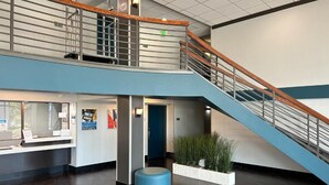 Eine moderne Lobby mit Treppe, einer Rezeption und einer Sitzgelegenheit.