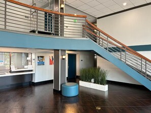 Un vestíbulo moderno con una escalera, una mesa de recepción y una zona de estar.