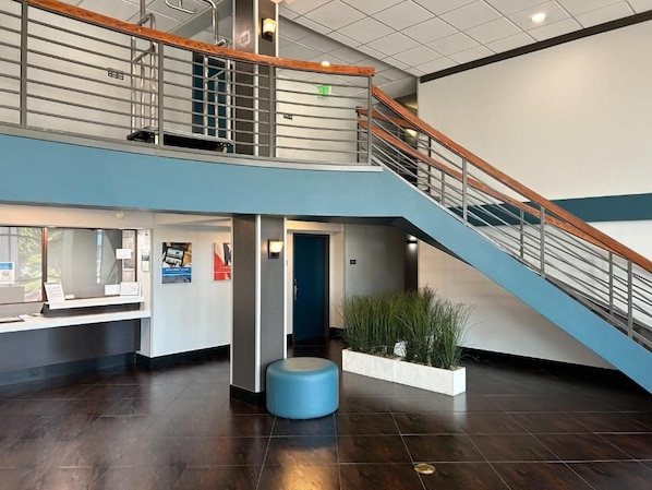 A modern lobby with a staircase, a reception desk, and a seating area.