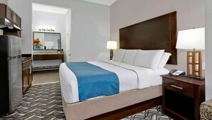 Una camera d'albergo con un letto, un comodino, una lampada e vista sul bagno.