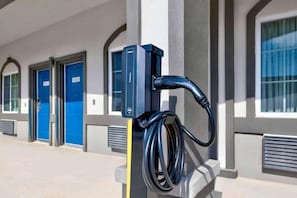 A parking meter with a charging station attached to a building facade.