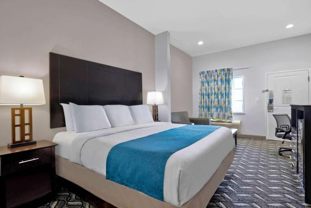 A hotel room with a large bed, two bedside tables, a desk, and a chair.