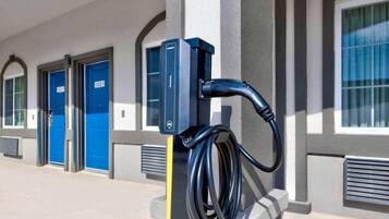 A parking meter with a charging station attached to a building facade.