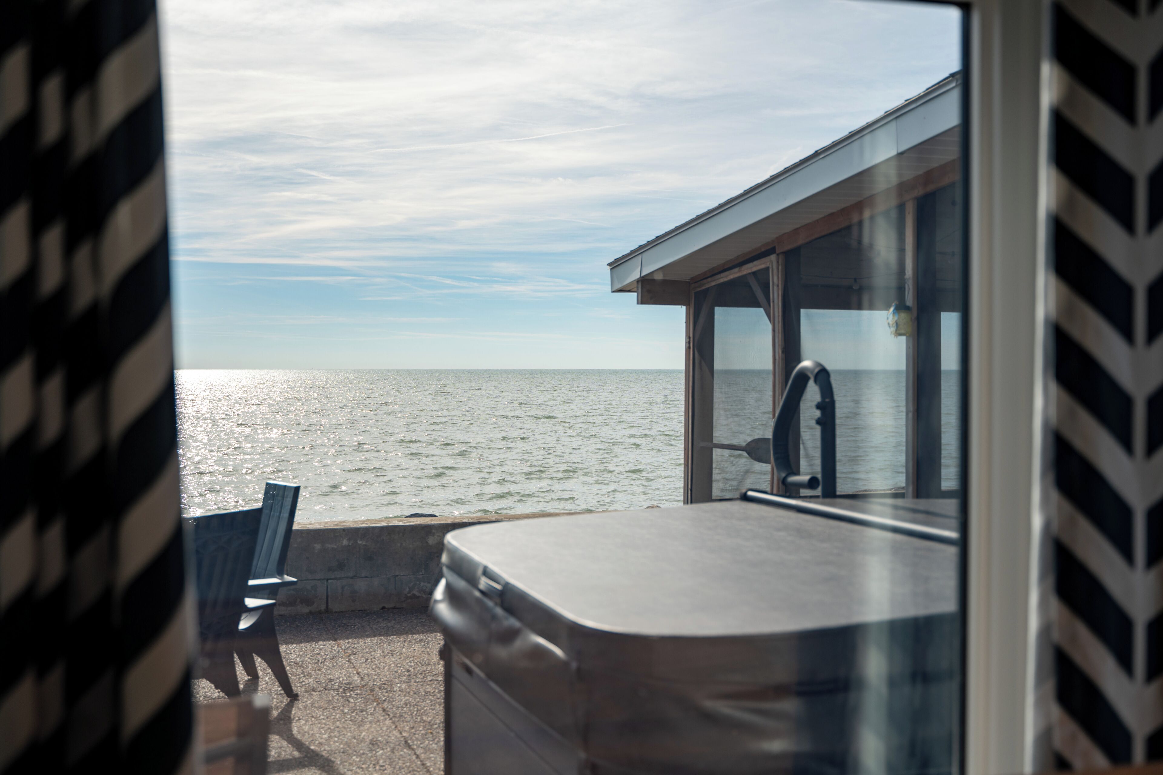 A room with a view of the sea, a window, and a chair.
