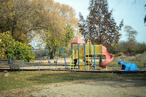 A playground with a slide, swings, and a climbing structure. - Peaceful 3-bedroom lake house with hot tub, and sauna.Birders paradise. (Amherstburg)