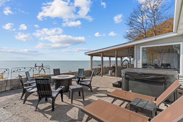 Eine Terrasse im Freien mit Sitzgelegenheiten und einem Grill, mit Blick auf ein Gewässer.