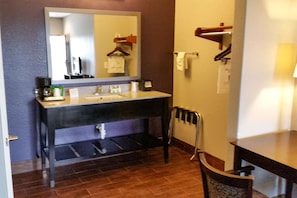 Baño con lavamanos, espejo, toallero y una silla.