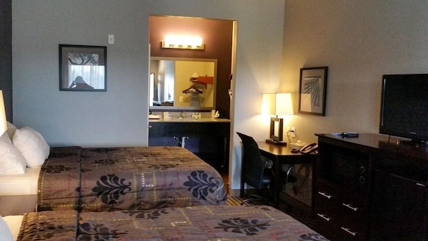 A hotel room with two beds, a desk with a lamp, a television, and a mirror. - Your Budget-Friendly Home Away from Home l 2 Queen Beds Suite (Beeville)