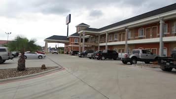 A hotel with multiple parking spaces, a covered parking area, and a building with a red facade and white trim.