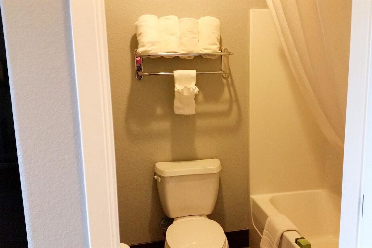 Un baño con inodoro, toallero con toallas y bañera.