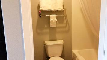Un baño con inodoro, toallero con toallas y bañera.