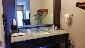 Un baño de hotel con lavabo, espejo, toallero y cafetera.