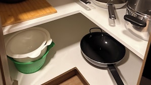 Een keuken met een houten aanrecht, diverse pannen en een groene zeef.