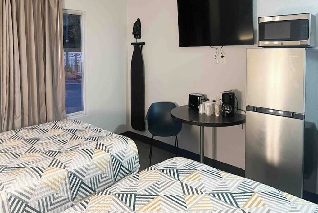 A room with a bed, a small table with a coffee maker, a TV, and a refrigerator.