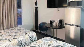 A room with a bed, a small table with a coffee maker, a TV, and a refrigerator.