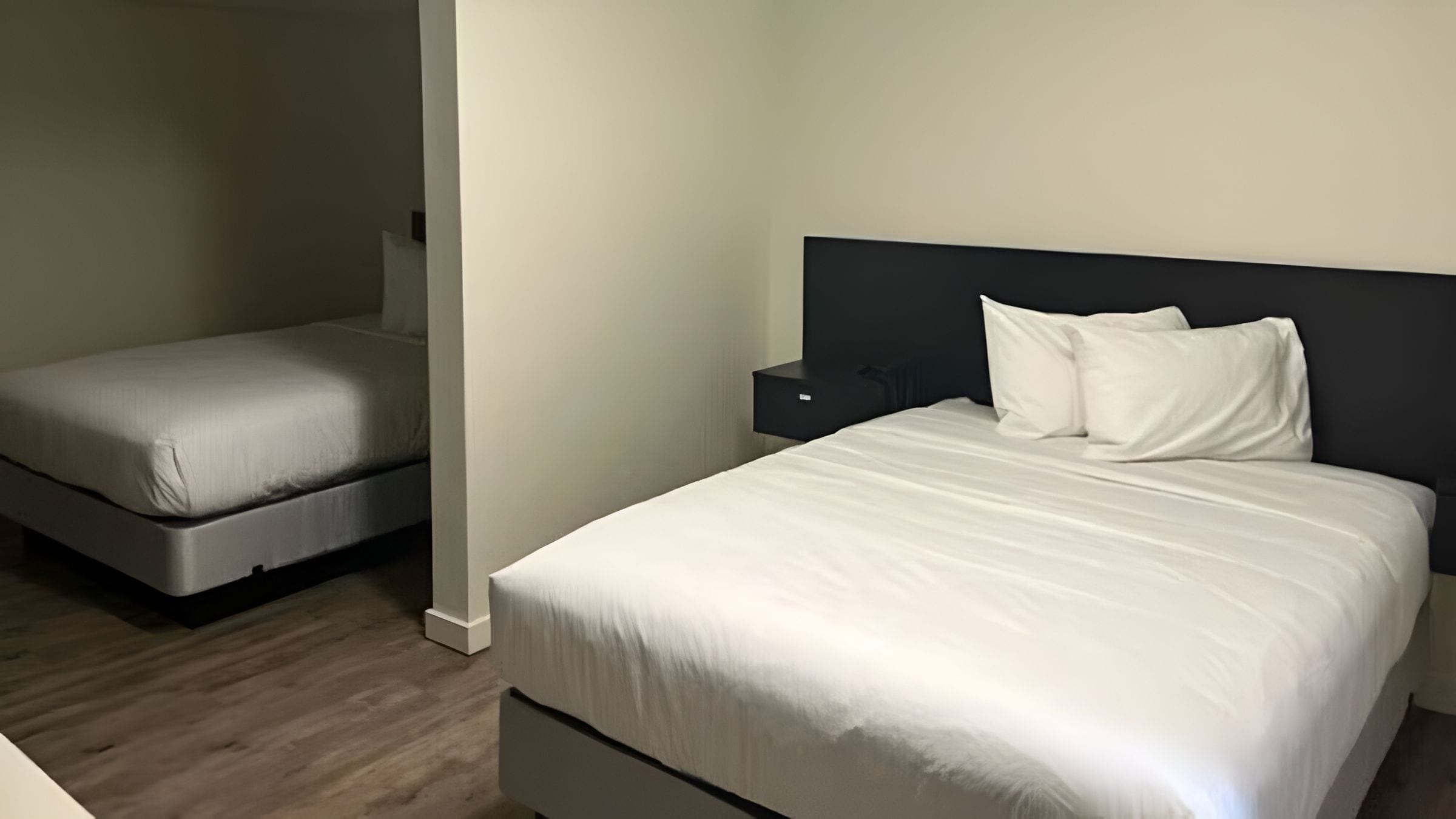 A bedroom with a large bed, a smaller bed, and a nightstand.