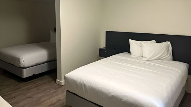 Quarto com uma cama grande, uma cama menor e uma mesinha de cabeceira.