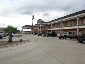 A hotel with multiple parking spaces, a covered parking area, and a building with a red facade and white trim.