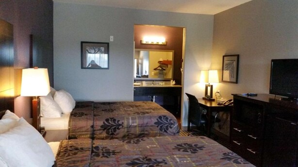 Ein Hotelzimmer mit einem Bett, einem Schreibtisch, einem Schminktisch und einem Fernseher.